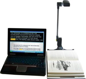 Picture of the Pearl camera scanner connected to an open laptop scanning a book. 